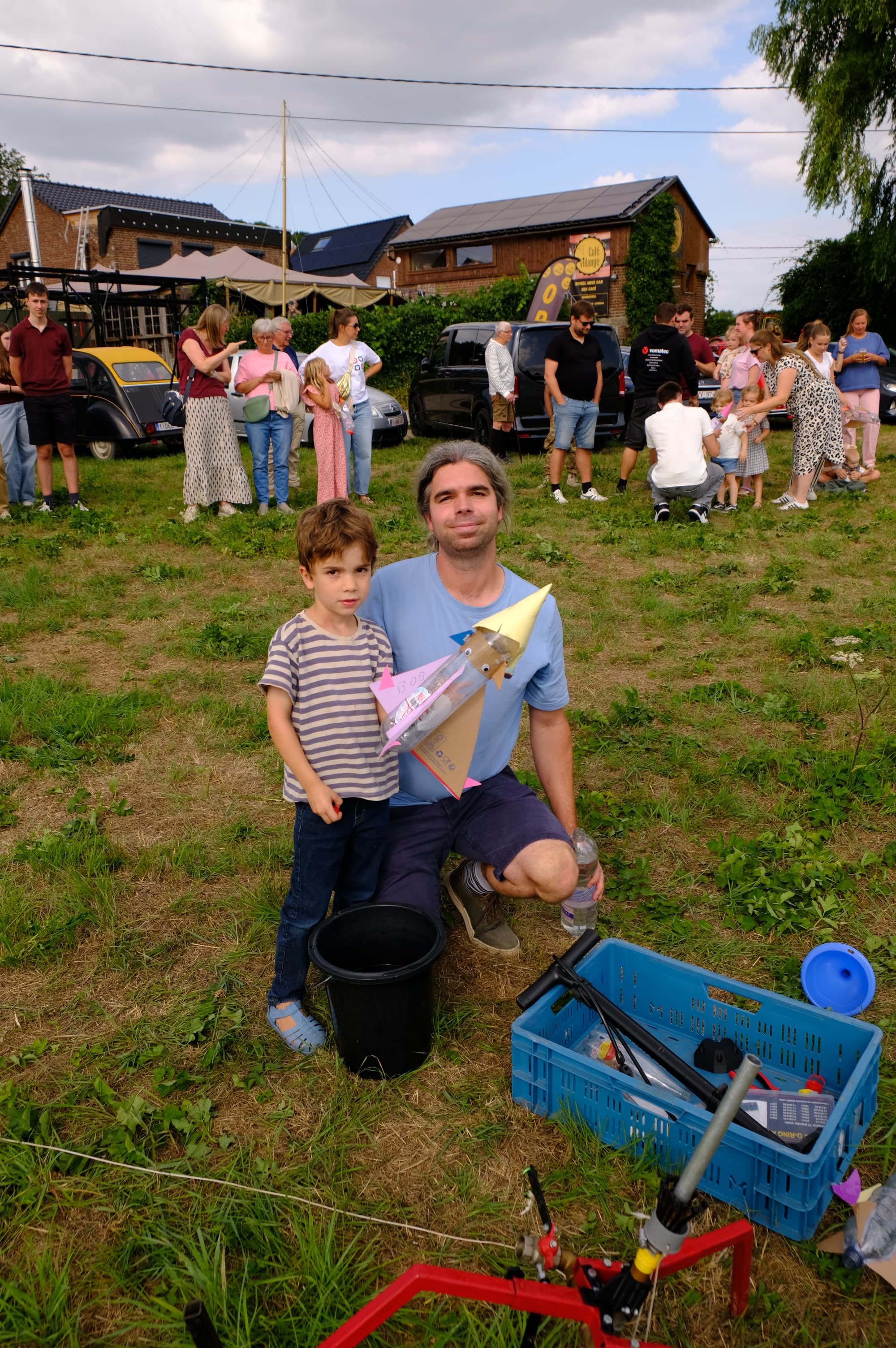 Two girls proudly holding a finished water rocket with cardboard wings.